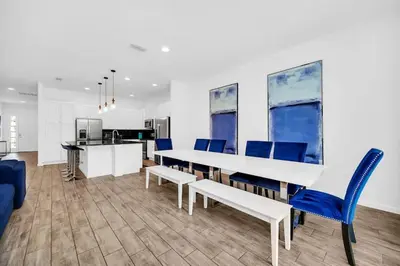 a dining room with a white table and blue chairs at EPIC 12 Bedroom Home with Private Pool in Kissimmee