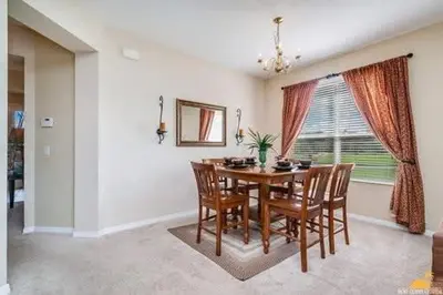 a dining room with a table and chairs and a window at BellaVida Palms Private Screened Pool Home in Kissimmee