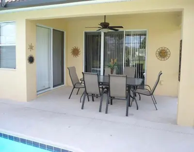 a patio with a table and chairs and a ceiling fan at BellaVida Palms Private Screened Pool Home in Kissimmee