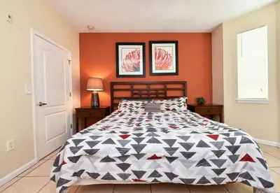 a bedroom with a large bed with orange walls at Resort Condo with all amenities needed-Cane Island in Kissimmee