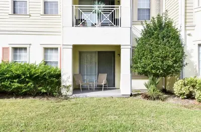 a white building with two chairs on a balcony at Resort Condo with all amenities needed-Cane Island in Kissimmee