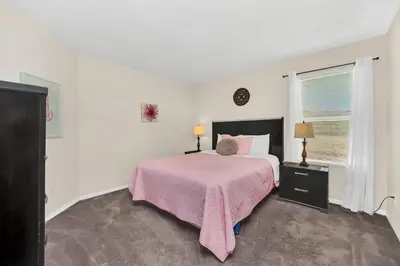 a white bedroom with a bed with a pink blanket at Remodeled 7 Bedroom Retreat Near Disney World in Kissimmee