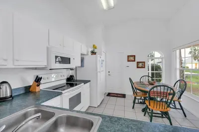 a kitchen with white appliances and a table with chairs at Cute Vacation Home Very Close to Disney in Orlando