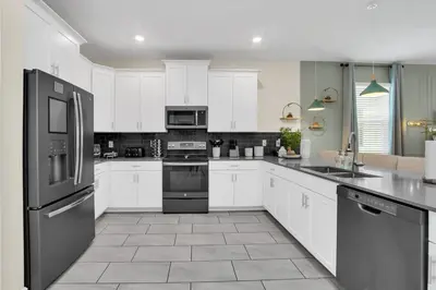 a kitchen with white cabinets and black appliances at Storey Lake Dream Villa with Private Pool in Kissimmee