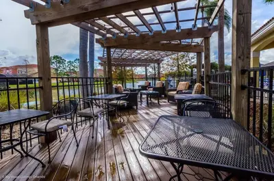 a patio with tables and chairs on a wooden deck at Wonderful Terra Verde Orlando Vacation Home in Kissimmee