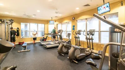 a gym with cardio equipment and people in the gym at 3 Bedrooms Condo Only Minutes From Disney in Orlando