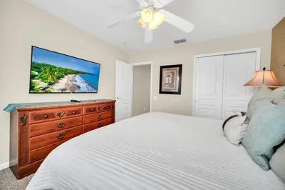 a bedroom with a bed with a dresser and a flat screen tv at Newly Upgraded Disney Themed Vacation Retreat in Orlando