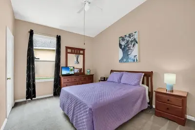 a bedroom with a purple bed and a tv at Windsor Palms Villa with Very Private Pool in Kissimmee