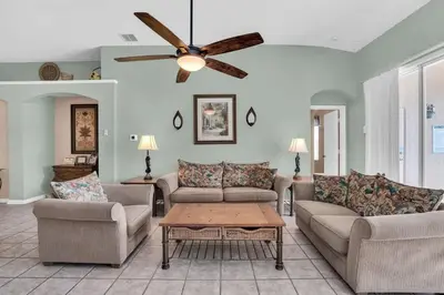 a living room with two couches and a ceiling fan at Windsor Palms Villa with Very Private Pool in Kissimmee