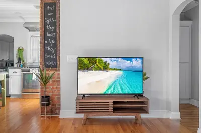 a television on a stand in a living room with a beach at Tiny Home w MIL suite - 3 MI to DT in Orlando