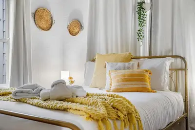 a white bed with a yellow blanket and pillows at Tiny Home w MIL suite - 3 MI to DT in Orlando