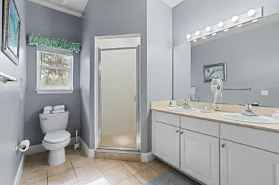 a bathroom with a toilet and two sinks and a shower at Casa 4Q Lucaya com Temas Disney e Clubhouse in Kissimmee