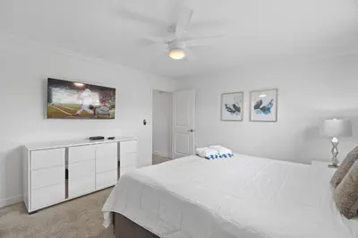 a white bedroom with a bed and a tv on the wall at Stunning home at Storey Lake close to Disney in Kissimmee
