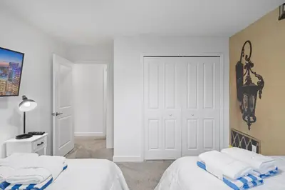 a white bedroom with two beds and a door at Stunning home at Storey Lake close to Disney in Kissimmee