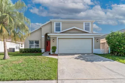 a house with a garage and a palm tree at Chatham House in Kissimmee