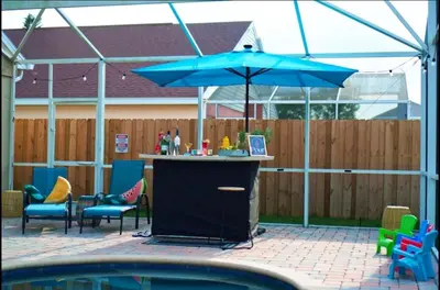 a patio with a bar with chairs and an umbrella at Chatham House in Kissimmee