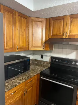 a kitchen with wooden cabinets and black appliances at Cozy Haven with Premier Privacy 4 bedroom in Orlando