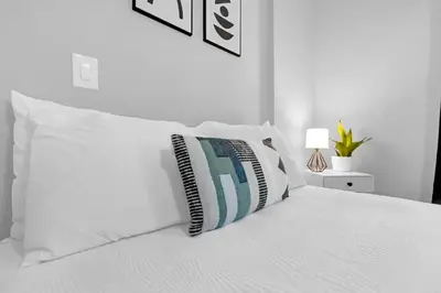 a white bed with white pillows on top of it at Modern Cuartito near Winter Park in Orlando