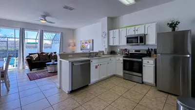 a kitchen with white cabinets and a stainless steel refrigerator at Tequilla Sunrise at Windsor Hills in Orlando