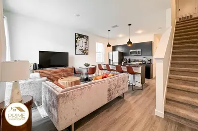 a living room with a couch and a kitchen at New 3BD3BA Townhouse Themed Near Disney in Kissimmee