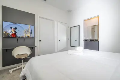a white bedroom with a white bed and a chair at 3221 Brand New Family 3BD Townhouse near Disney in Kissimmee