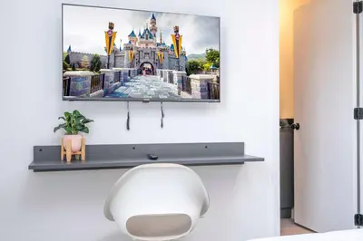 a room with a tv on a wall with a white chair at 3221 Brand New Family 3BD Townhouse near Disney in Kissimmee