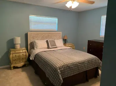 a bedroom with a bed and two night stands and two windows at Lakefront Home Where You Can Retreat and Relax in Orlando