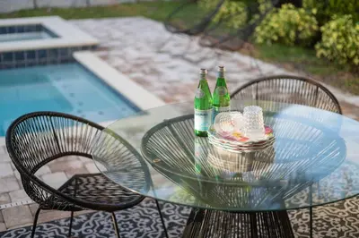 a glass table with two bottles on it with two chairs at Private Heated Pool Billiard lounge 6MI to Disney in Orlando
