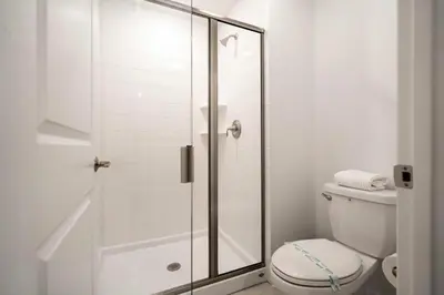a white bathroom with a shower and a toilet at 2557 Awesome Family 4BD Townhouse located at Storey Lake in Kissimmee