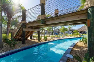 a wooden bridge over a swimming pool with a blue swimming pool at 2557 Awesome Family 4BD Townhouse located at Storey Lake in Kissimmee