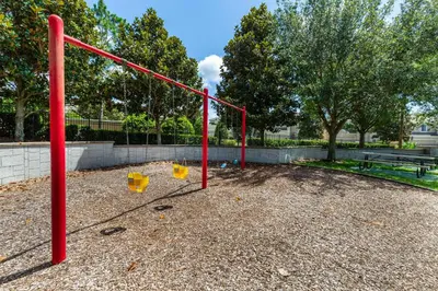 a playground with a red swing set in a park at Windsor Hills Condo: Water Park Included in Orlando