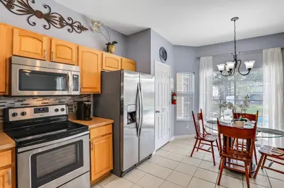 a kitchen with a stainless steel refrigerator and a table at Family Fun Haven: Spacious Villa Water Park in Orlando