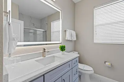 a bathroom with a sink and a mirror and a toilet at Group Getaway Paradise: Large Home Water Park in Orlando