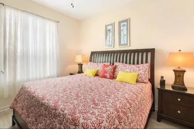a bedroom with a bed with red and yellow pillows at Windsor Hills Getaway: Condo with Water Park in Orlando
