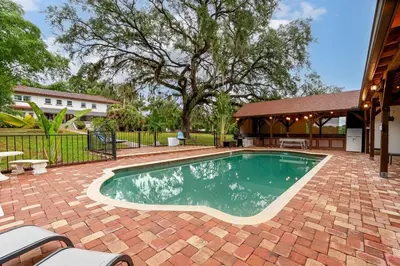 a swimming pool in a brick yard with a house at 6 Bedroom Historic Home in Orlando