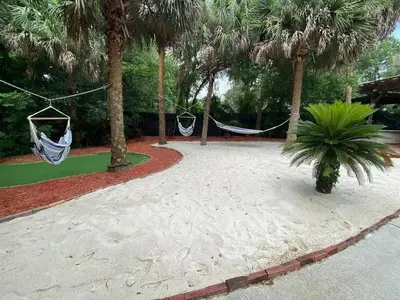 two hammocks hanging from palm trees in a garden at Themed Speak Easy with Pool, Hot Tub, & Lake in Orlando