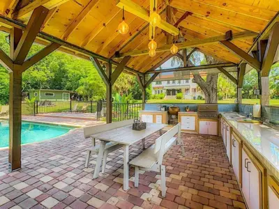 an outdoor kitchen with a table and a pool at Themed Speak Easy with Pool, Hot Tub, & Lake in Orlando