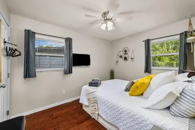 a bedroom with a bed with a ceiling fan and two windows at New Design-Movie Night Bar-Fire Pit-Hammocks-Games in Orlando