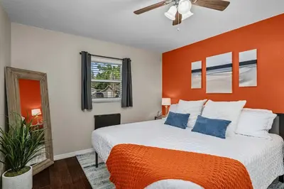 a bedroom with a bed with an orange wall at New Design-Movie Night Bar-Fire Pit-Hammocks-Games in Orlando