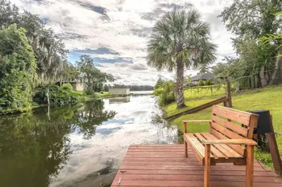 a wooden bench sitting on a wooden dock next to a river at Large Deck, Lakefront, Yard Games in Orlando