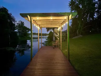 a wooden boardwalk with a pergola next to a river at Large Deck, Lakefront, Yard Games in Orlando