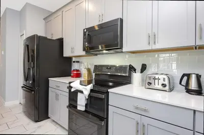 a kitchen with white cabinets and a black refrigerator at Stunning 4Bd Close to Disney with Pool at Storey Lake 4369 in Kissimmee