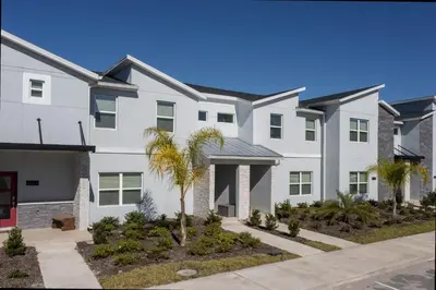 a white house with a palm tree in front of it at Stunning 4Bd Close to Disney with Pool at Storey Lake 4369 in Kissimmee