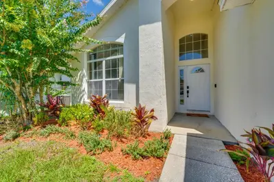 a white building with a white door and plants at 15 Mi to Universal Home with Pool in Kissimmee