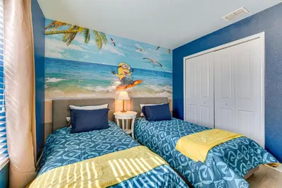 two beds in a room with a painting of the ocean at Private Pool and Game Room Family Vacation Rental in Kissimmee