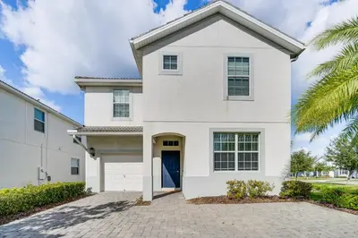 a white house with a palm tree at Private Pool and Game Room Family Vacation Rental in Kissimmee