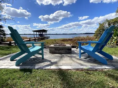 two blue chairs sitting on a patio near the water at Lakefront Guest House By Downtown, Boat, Fishing in Orlando