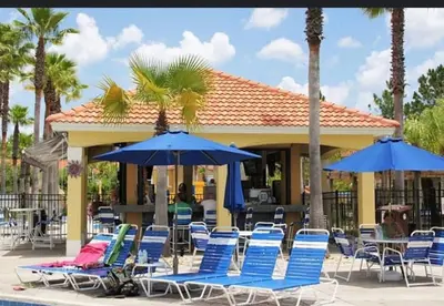 a group of chairs and umbrellas next to a pool at Vacation Home near Disney World! in Kissimmee