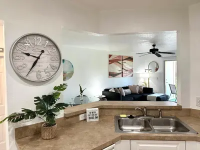 a kitchen with a clock on the wall and a living room at Modern 2BR Lakeview Near Orlando Airport Free Parking in Orlando