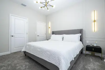 a white bedroom with a large bed and a chandelier at Storey Lake 4Q/3B acesso Resort e Piscina Priv. in Kissimmee